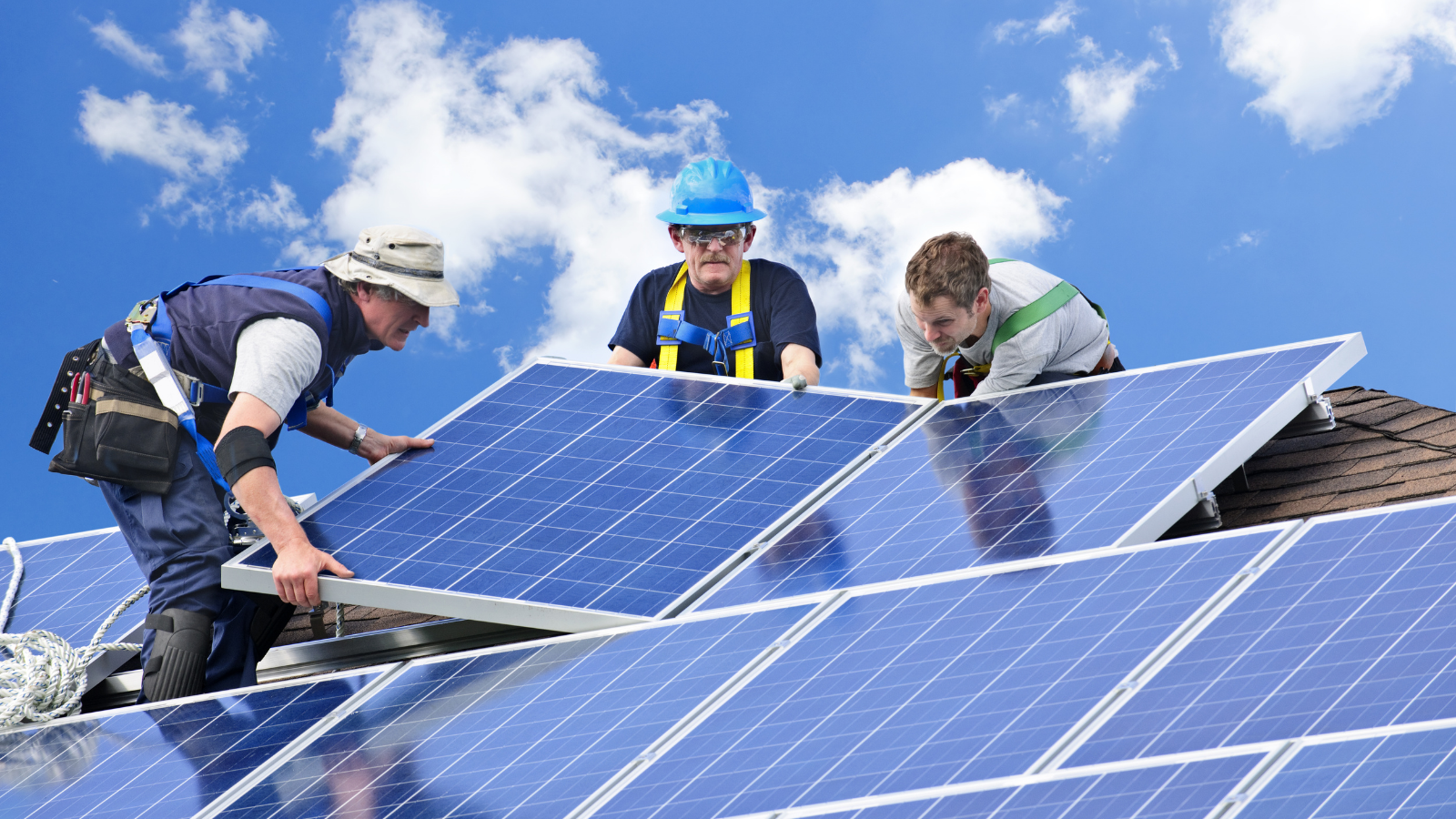 Installatie van Power Solar Energy zonnepanelen door technici op een dak onder een heldere lucht