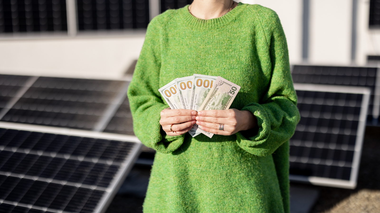 Persoon houdt geld vast als symbool voor besparing door zonnepanelen