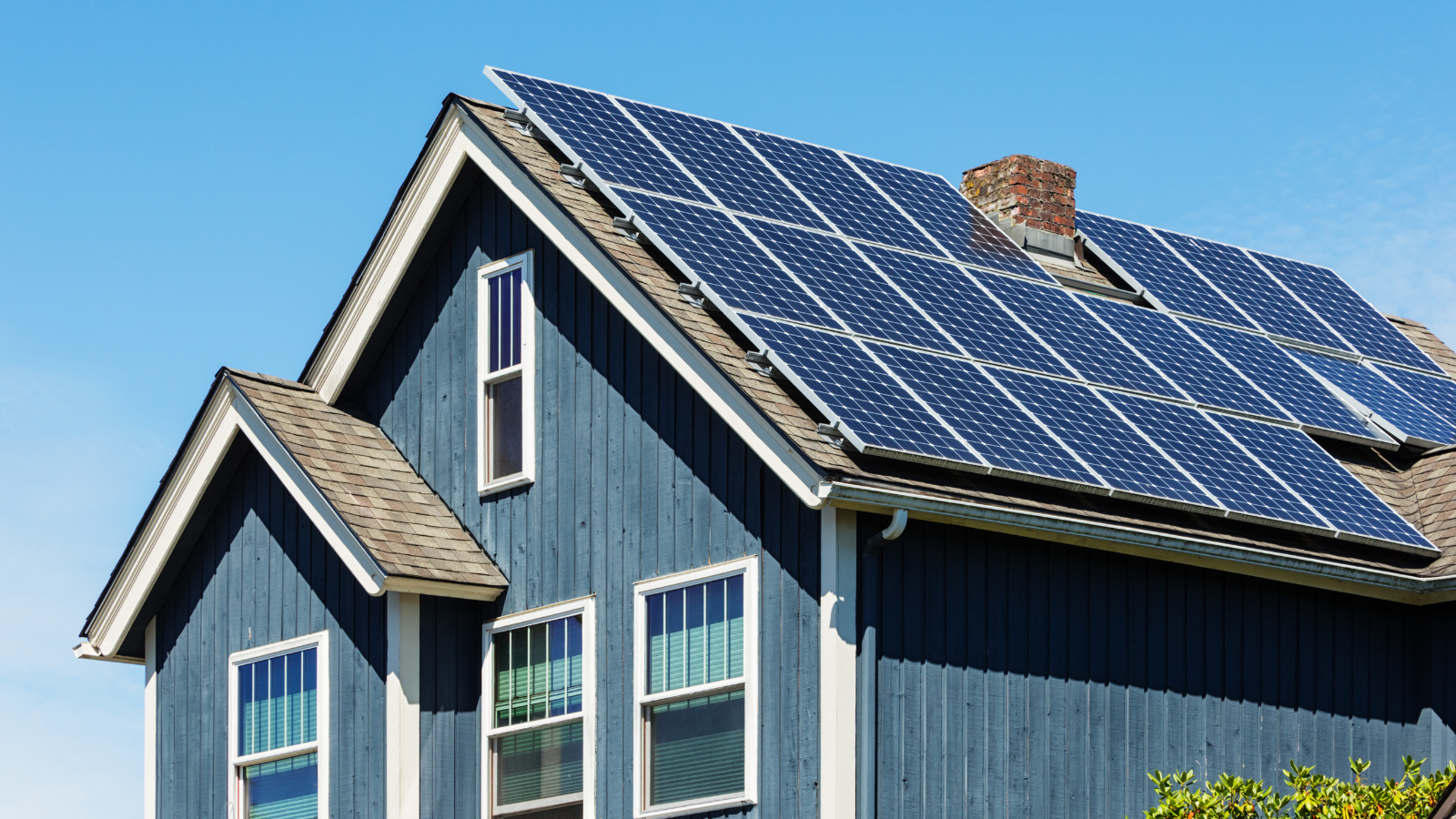 Zonnepanelen geïnstalleerd op het dak van een huis, die duurzame energie opwekken onder een heldere blauwe lucht.